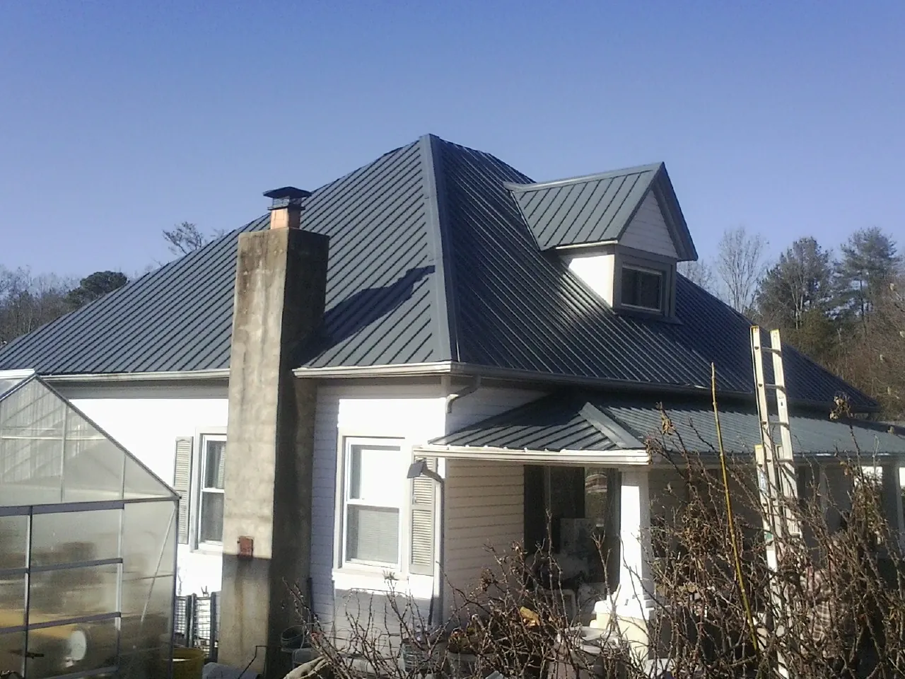 Dark blue standing seam metal roof on a white farmhouse with dormer — Slate & Tile Roof Repair by Roofing Brothers in Autryville