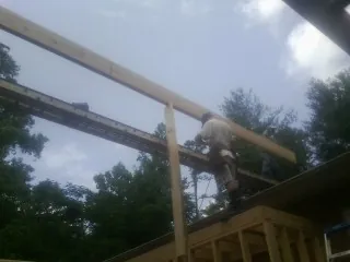 Carpenter setting a ridge beam over a new addition frame — Ice Dam Removal by Roofing Brothers in Autryville