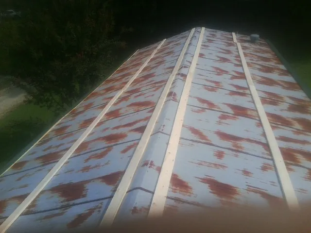 Rusted metal roof panels with new wood purlins before replacement — Storm Damage Roof Repair in Autryville by Roofing Brothers