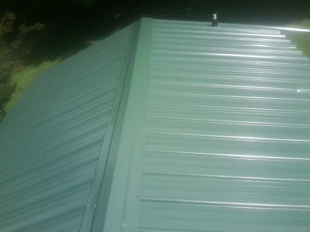 New green metal panels meeting at the ridge of a roof in Autryville