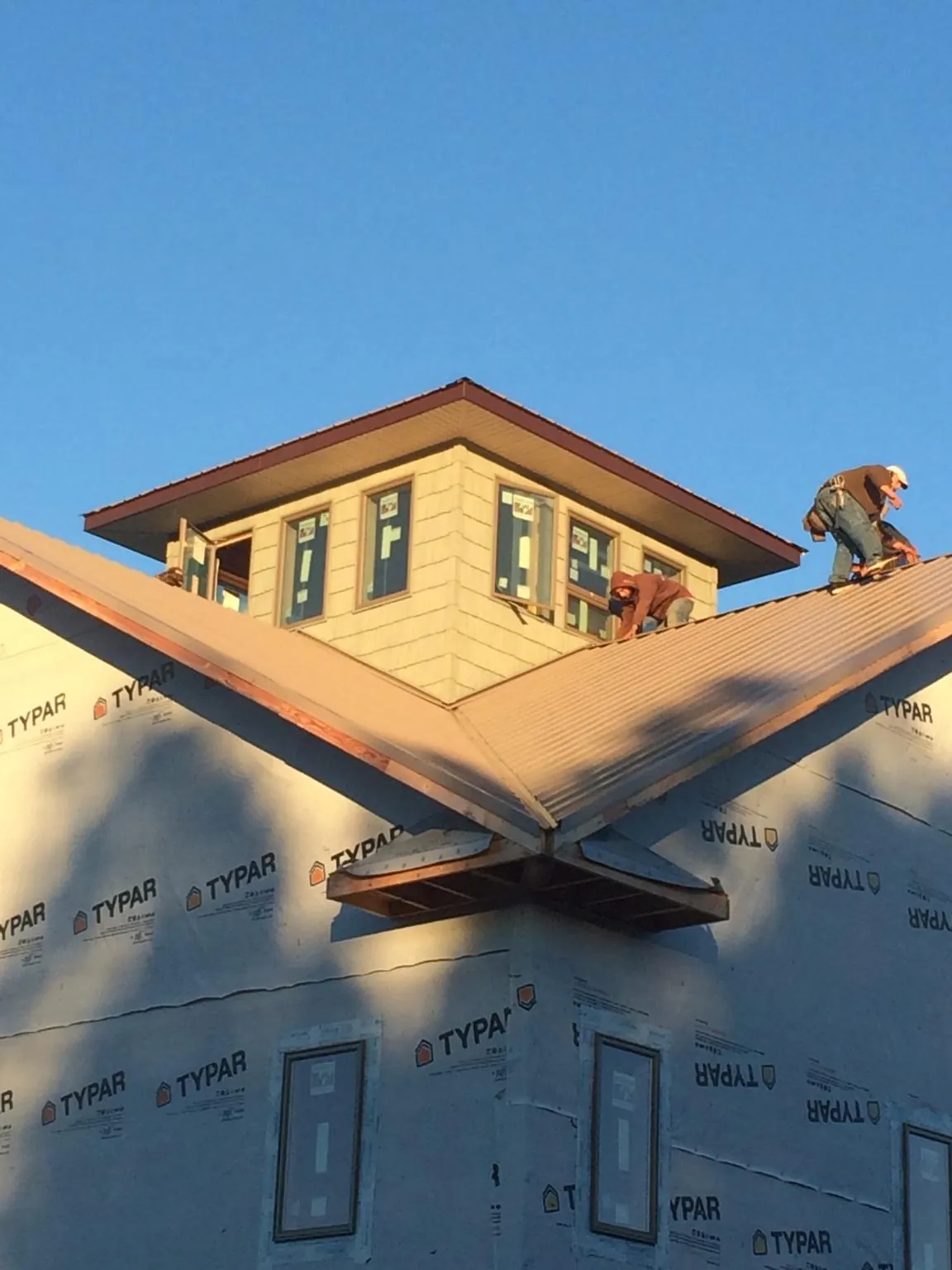Roofers working around a rooftop cupola on a new metal roof at sunset — Roof Waterproofing in Autryville by Roofing Brothers